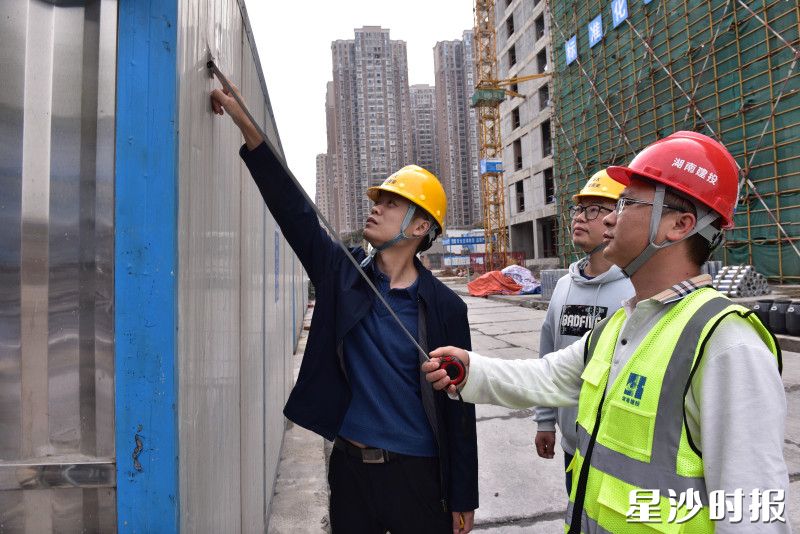 县住房城乡建设局工作人员在建筑工地检查是否使用规范材料。