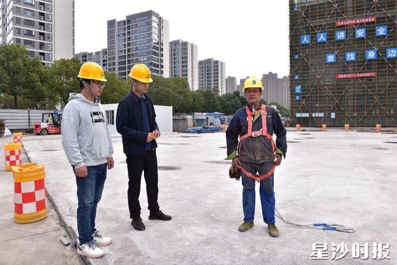 县住房城乡建设局工作人员在建筑工地检查现场人员五点式安全带佩戴是否符合规范要求。