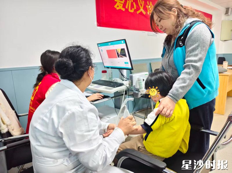 孩子在老师的陪同下,接受医护人员的免费体检。