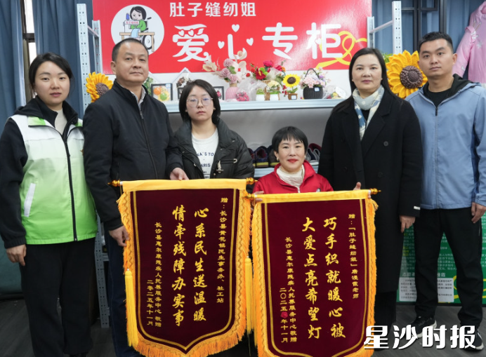 惠尔康托养中心相关负责人将两面锦旗分别交到受赠者手上并合影。均为火统维 摄