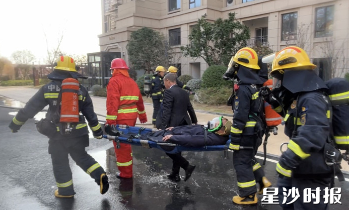 消防救援人员模拟将伤者抬至室外空旷地带。