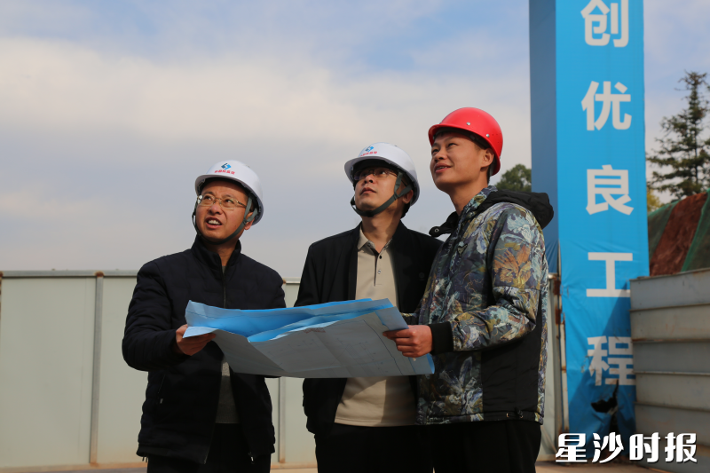 项目建设现场，工作人员手持施工图纸进行检查。