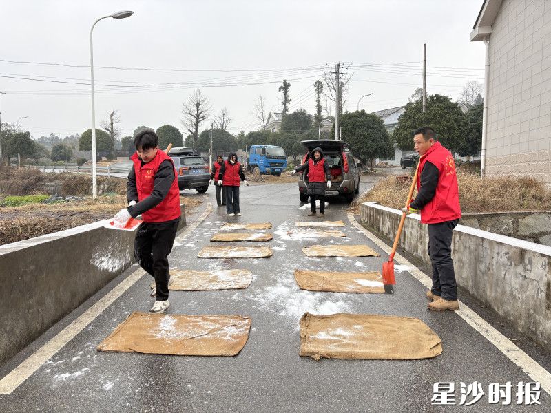 金井镇湘丰村党员干部在村内桥梁路段挥洒工业盐，铺就一条条温暖坚实的“平安路”。