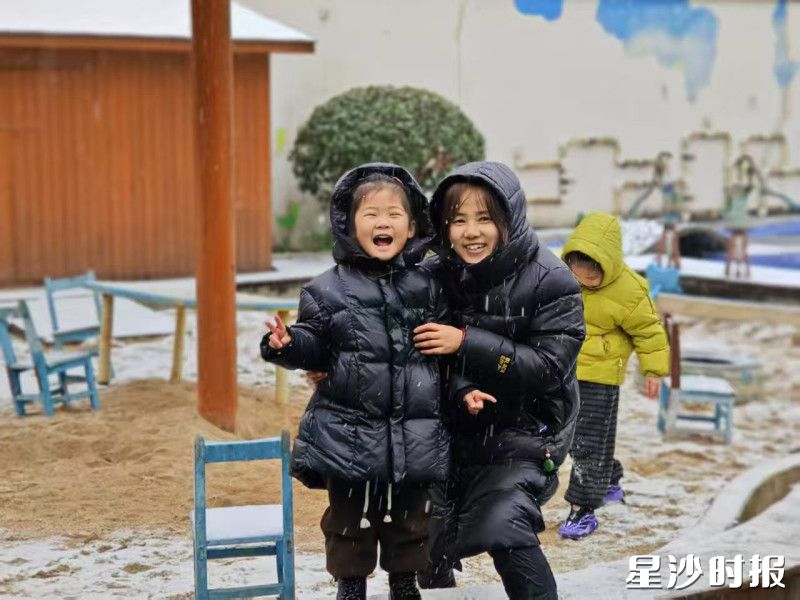 在㮾梨街道中心幼儿园，孩子笑得眼睛都弯成了月牙，身旁的老师也跟着笑出了声，雪花落在他们的帽檐和肩头，成了最好的点缀。