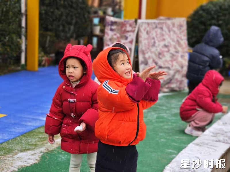 在㮾梨街道中心幼儿园，小朋友们眼神亮晶晶的，仰起脸，伸手去接落下的雪片。
