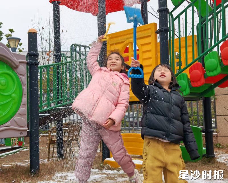 在㮾梨街道福天星雅苑幼儿园彩，两个小女孩踮起脚，把小铲子举得高高的，她们的快乐就像这飞扬的雪，简单又直接。