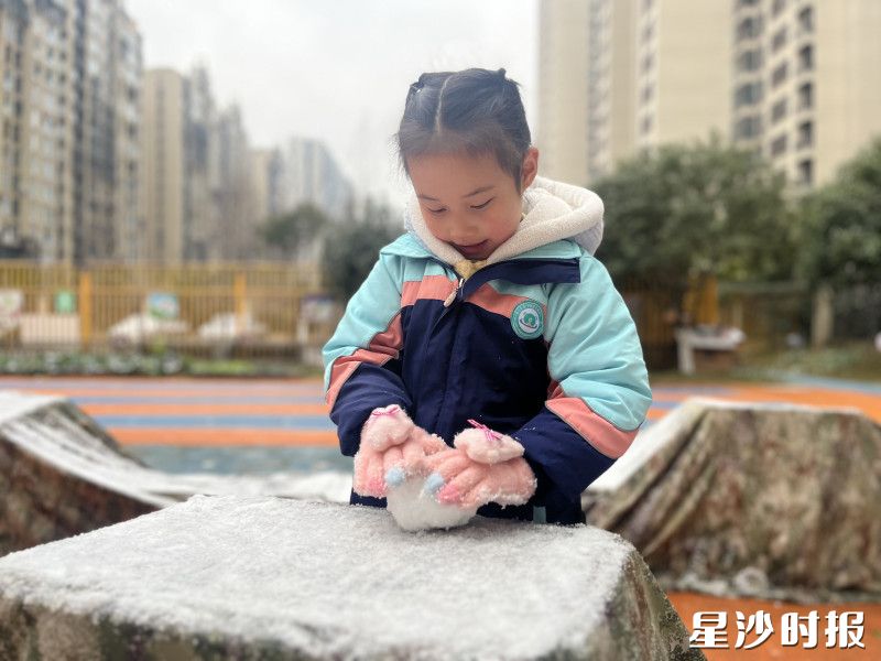 在东樾城幼儿园，小女孩戴蹲在落了薄雪的石台上，正专心地团着一小团雪。眼睛盯着手心的雪团，仿佛在捏着一份冬日独有的小惊喜。