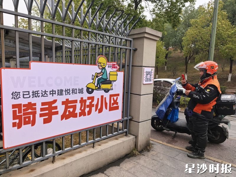 骑手在小区门口扫码通行。县住房城乡建设局供图