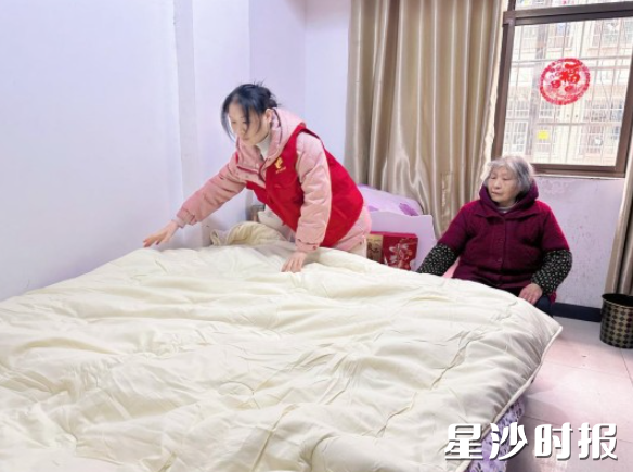 社工为老人铺上崭新的被褥。社区供图