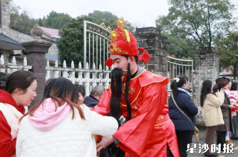 手持金元宝的“财神爷”为群众送上糖果。