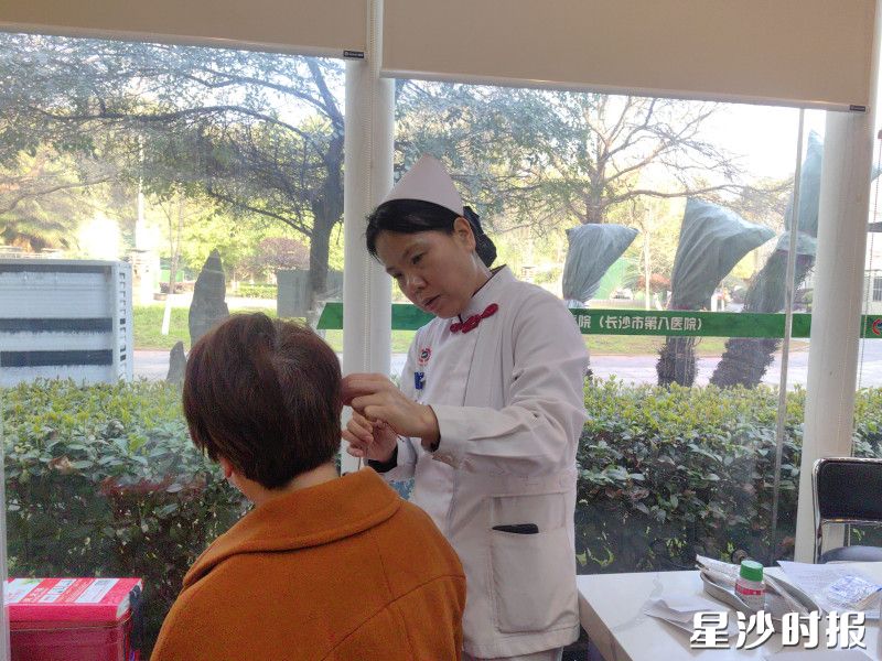 图为护士在为患者耳穴压豆调理。