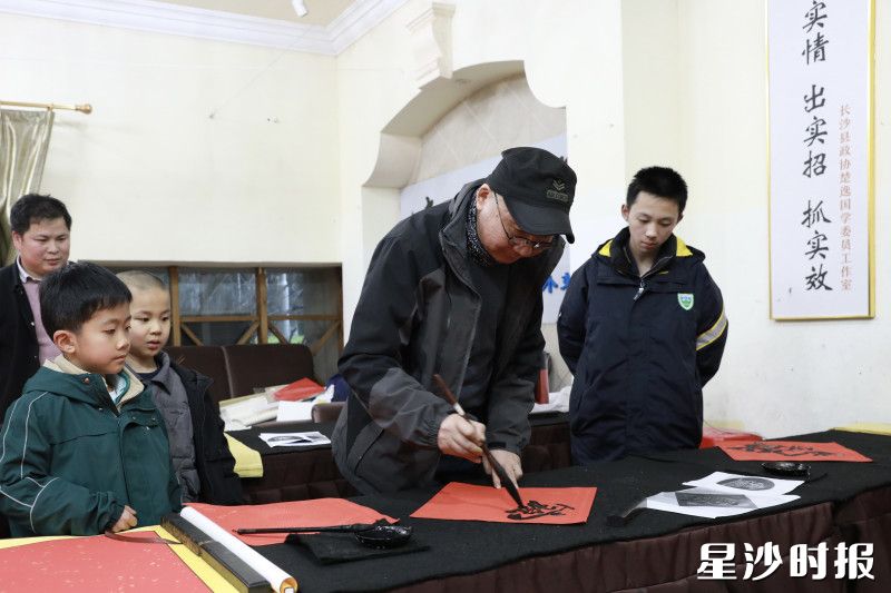 活动现场，省政协委员袁绍明为青少年展示书法。周汝洁 摄