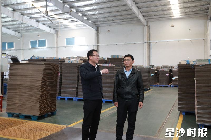 在长沙康乐包装有限公司的生产车间，周国俊（左）与企业负责人面对面交流。均为周汝洁 摄