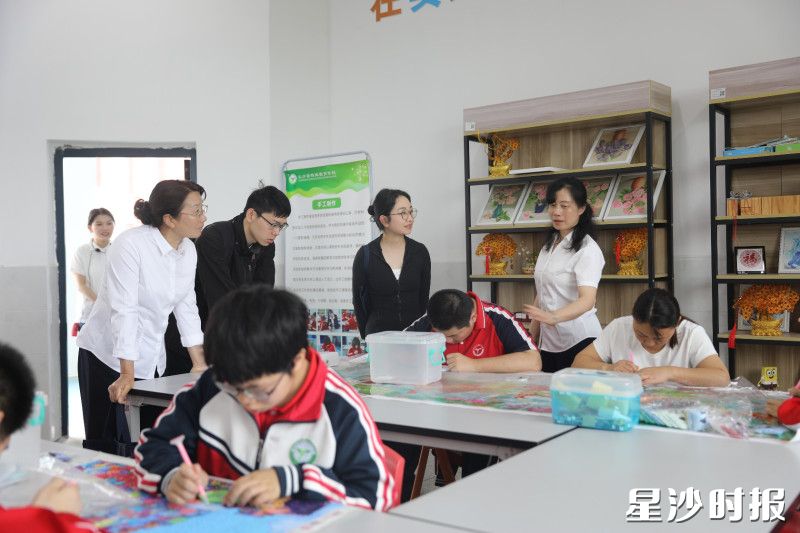 图为研修班成员参观钻石点画课堂，学生们聚精会神地完成作品。