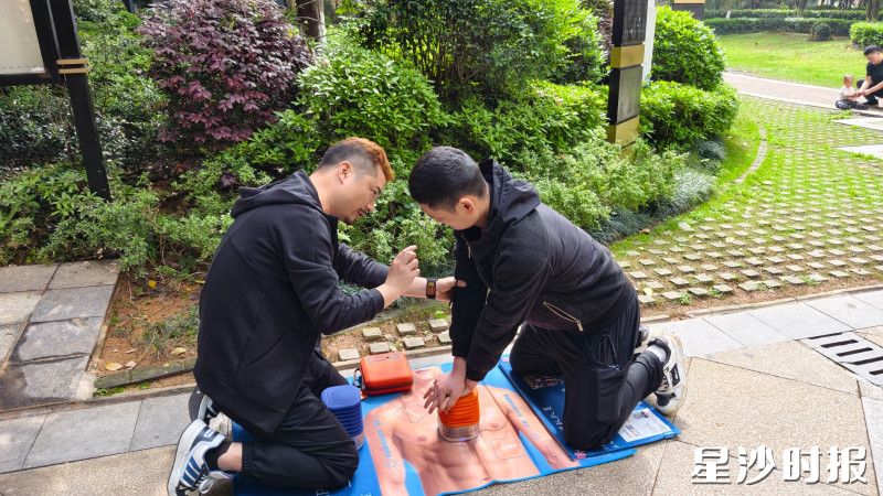 易卓跪在蓝色CPR教学垫旁，手把手向居民传授心肺复苏技能。均为受访者供图