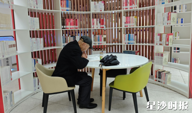 图书馆内，一位老者在专心阅读。