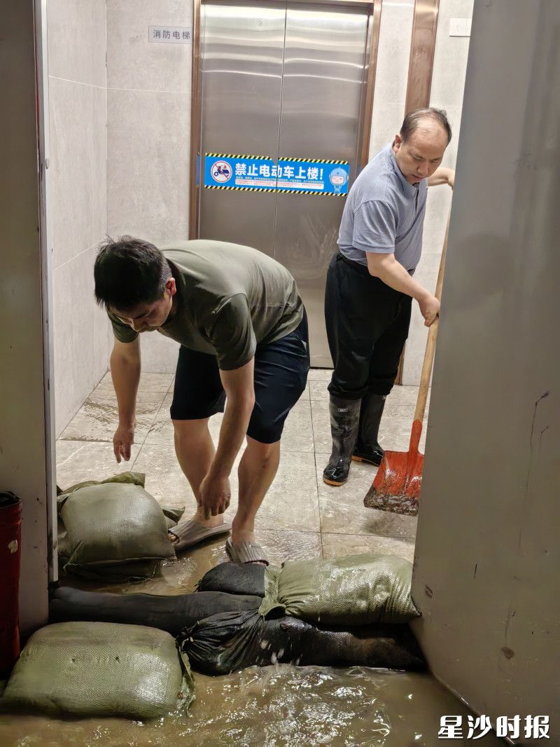 长沙县住房和城乡建设局工作人员通过堆沙袋阻止雨水蔓延进电梯。