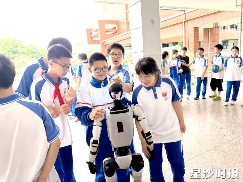 长沙县第一中学圣和学校学生与机器人互动。