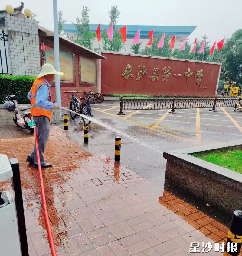 长沙县第一中学，环卫工人在冲洗路面。