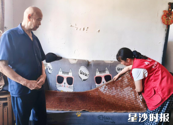 党员社工周卓给马桂华老人铺上凉席沙发垫。社区供图 党员社工周卓给马桂华老人铺上凉席沙发垫。社区供图