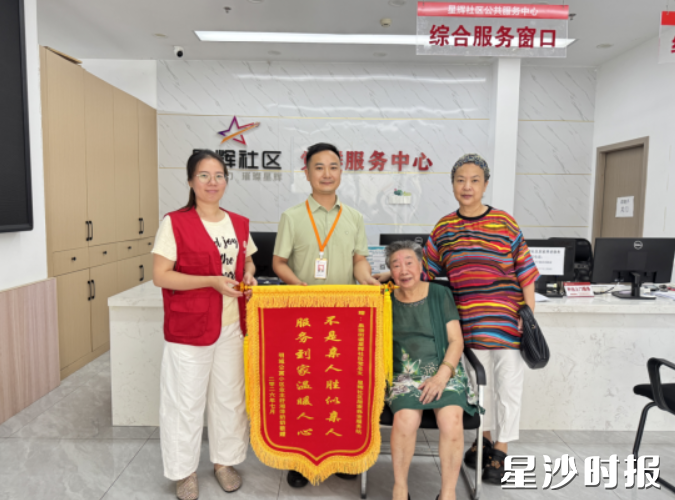 老人舒湘萍（右二）在女儿的陪同下，将一面锦旗送至星辉社区党总支书记粟丁（左二）及唯爱社工吴小银（左一）手中。社区供图