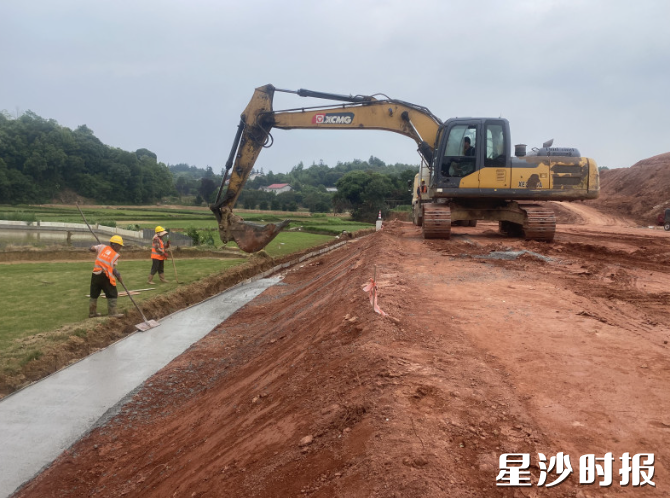 红棕土坡上工程机械轰鸣作业，大型挖掘机挥动铲斗平整土方、修整路基。县重点建设项目事务中心供图