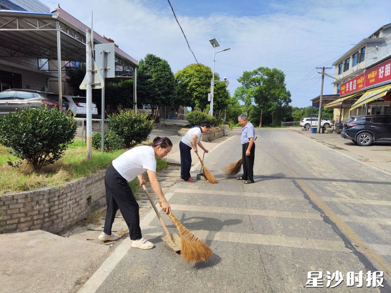 村干部和吴利红（中））帮老人（右）收拢玉米。安沙镇供图