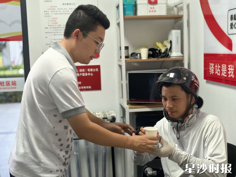 在驿站，跑腿小哥接过工作人员递来的水歇歇脚。
