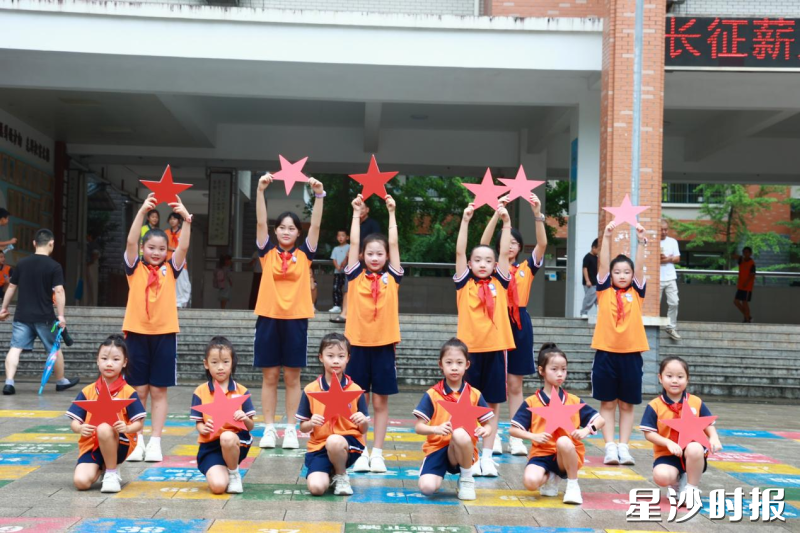 长沙市龙塘小学的同学们手持红色星形道具在校园前合影,定格 “星少年” 向阳成长的瞬间。