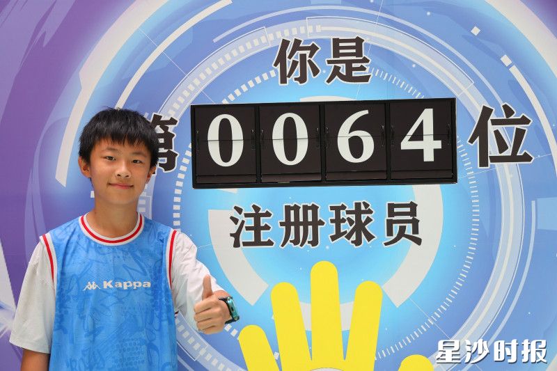 长沙华夏学校开学日设置“湘超”打卡点位,学生在“第 0064 位注册球员”展板前留影,感受体育带来的乐趣。