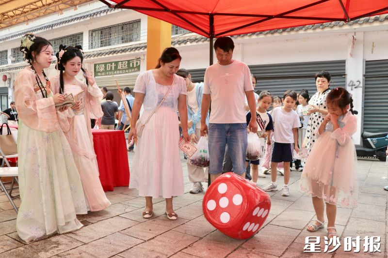 游客们在三仙街非遗集市上体验互动小游戏得银票活动。