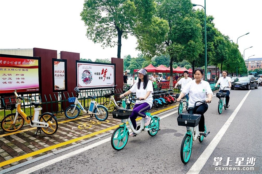 图为小塘路社区志愿者带头骑共享单车上下班，倡导绿色出行。
