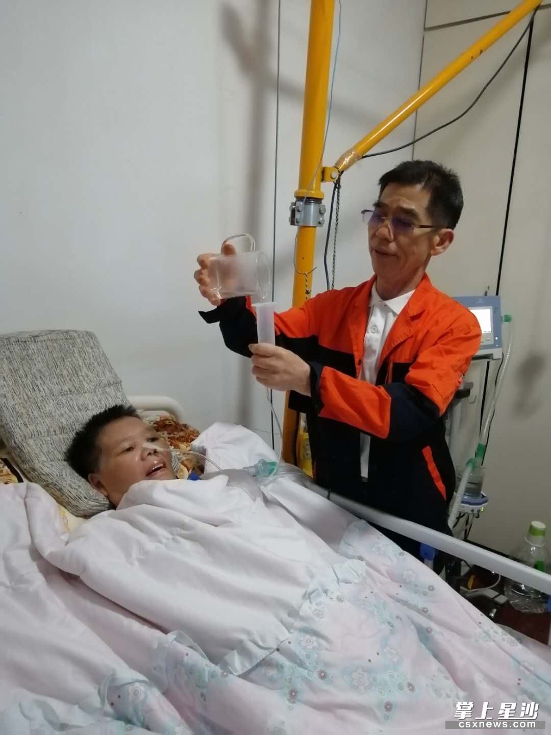 刘建军正在给瘫痪在床的妻子通过鼻饲管帮妻子喝水.资料图