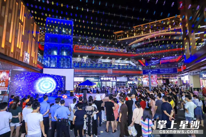 吾悦夜市内人流如织，市民在中心广场欣赏精彩的魔术表演。