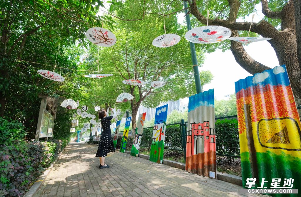 色彩鲜艳，风格明快的幼儿作品吸引了行人驻足观看并拍照。章帝 摄