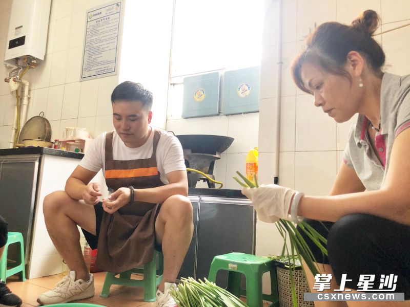 公司小伙赵雄（中）正在公司厨房和员工一起择菜。 均为宋彬彬 摄
