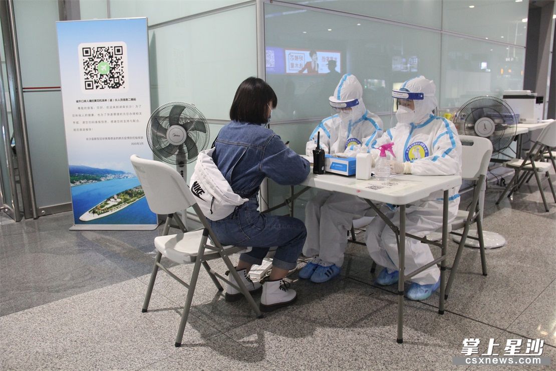 在长沙黄花国际机场，医务人员正在对旅客进行体温监测和人员去向排查。陈盼 摄