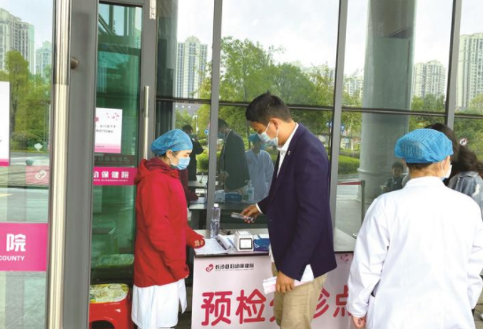 10月18日，居民在长沙县妇幼保健院入口的预检分诊台前扫描健康码。 李俊伟 摄