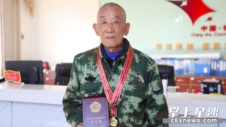 图为黄香林向记者展示他收到的中国人民志愿军抗美援朝出国作战70周年纪念章。 盛磊 摄