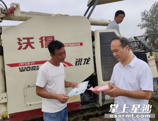 禁烧宣传巡查小分队队员正在向金龙村种粮大户张勇发放禁烧宣传单。