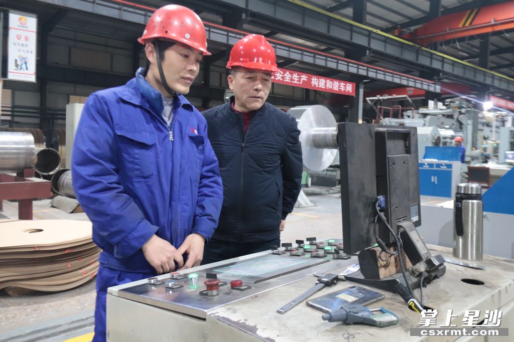 图为杨新远(右)在厂房内与工人交流。杨源 摄