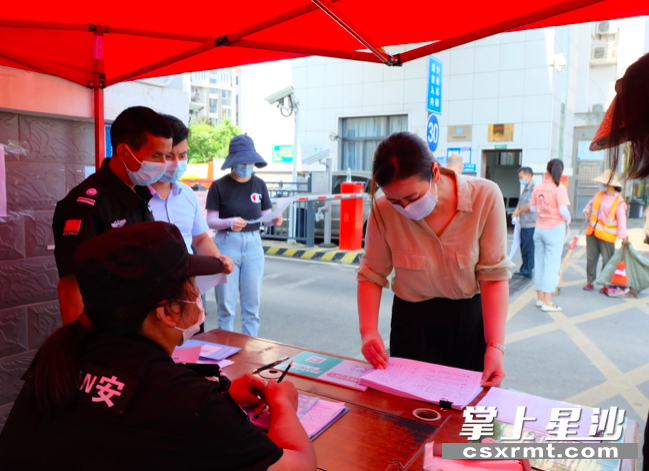 长沙县委常委,宣传部长杨溢在查看小区人员出入登记表.均为李丹 摄