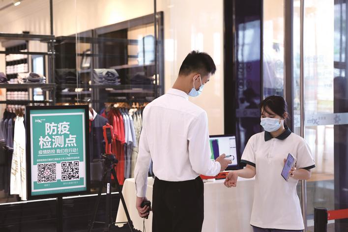 图为万象汇商场工作人员对进入市民测体温,检查"两码". 盛磊 摄