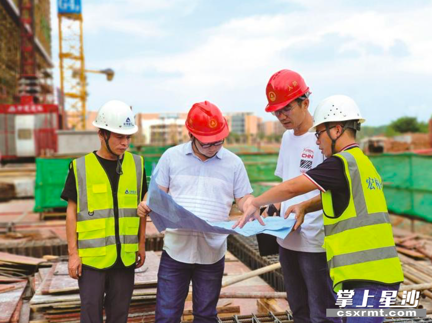 长沙县人防办工作人员正在对明月春溪府一期项目内的人防工程建设项目对照图纸与项目相关负责人进行细致核对。