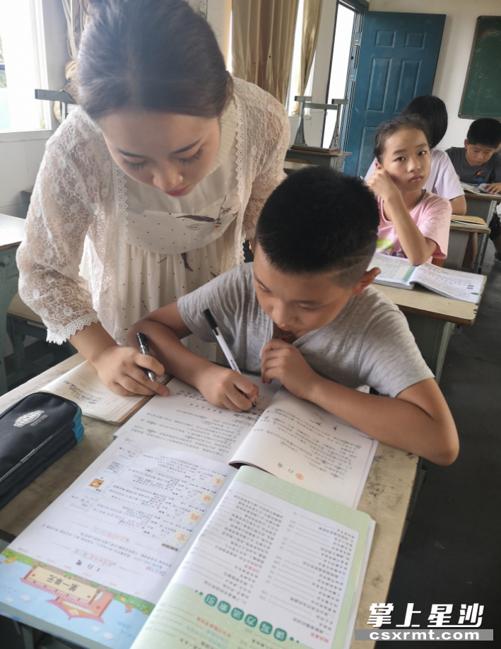 在长沙县北山镇合心小学,老师在辅导高年级学生作业学校供图