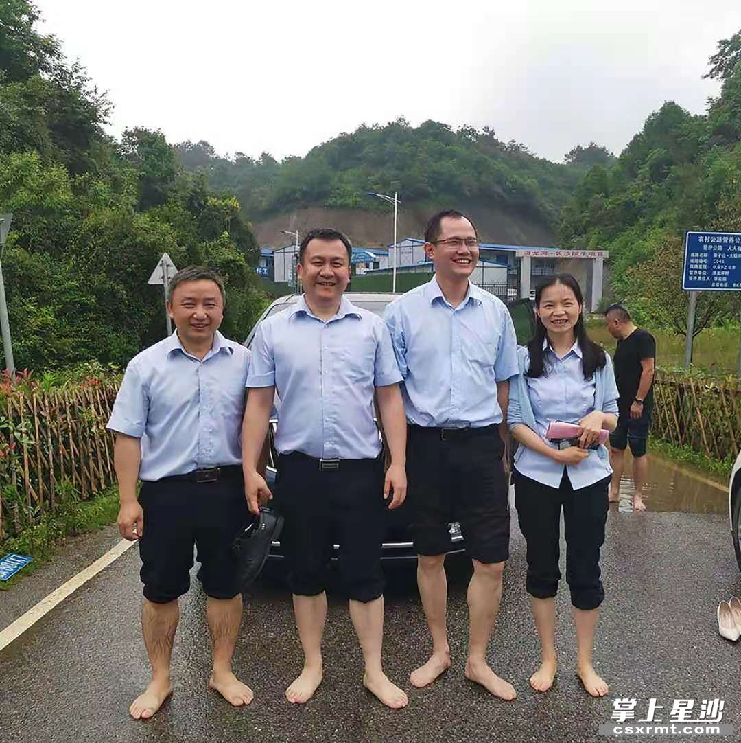 何金胜（左一）与同事们在开展乡村金融工作中突遇暴雨，乡间小路泥泞不堪，他们就脱下鞋子卷起裤腿，化身“赤脚大仙”将车子推过漫水的路面。均为供图