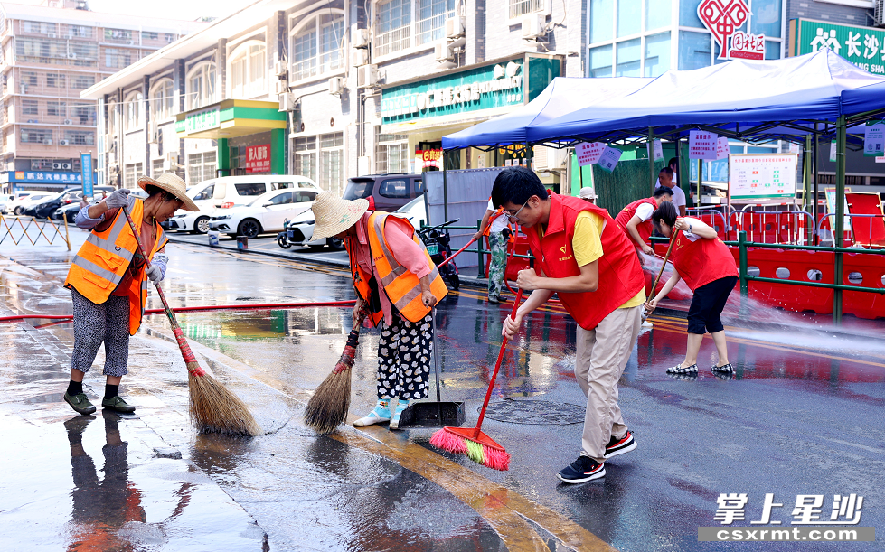 街道工作人员与环卫工人一起在龙塘菜市场周边清洗路面。 盛磊 摄