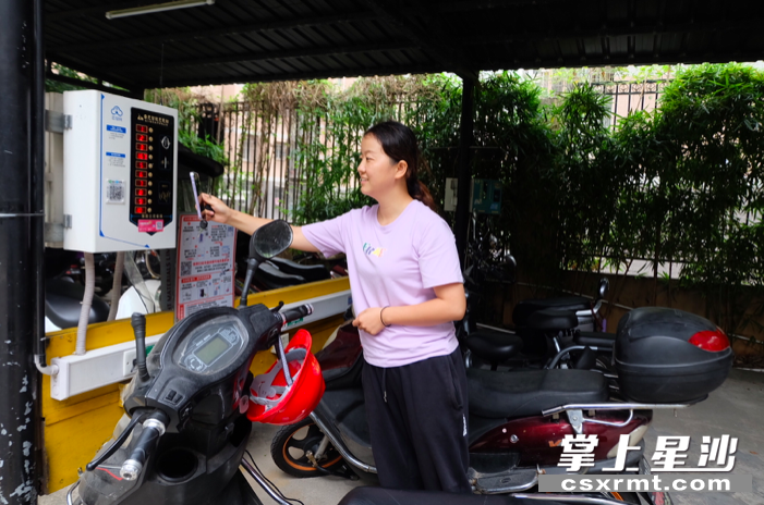 在三一街区小区内，小区业主杨慧正打开手机扫码打算给车辆充电。李丹 摄