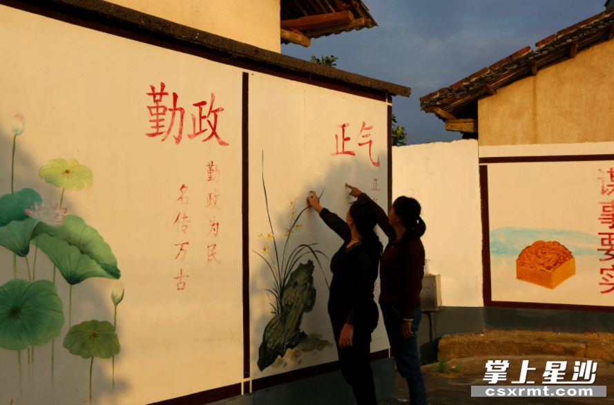 金江新村文化墙，经常引得群众驻足观看。梁焕鑫 摄