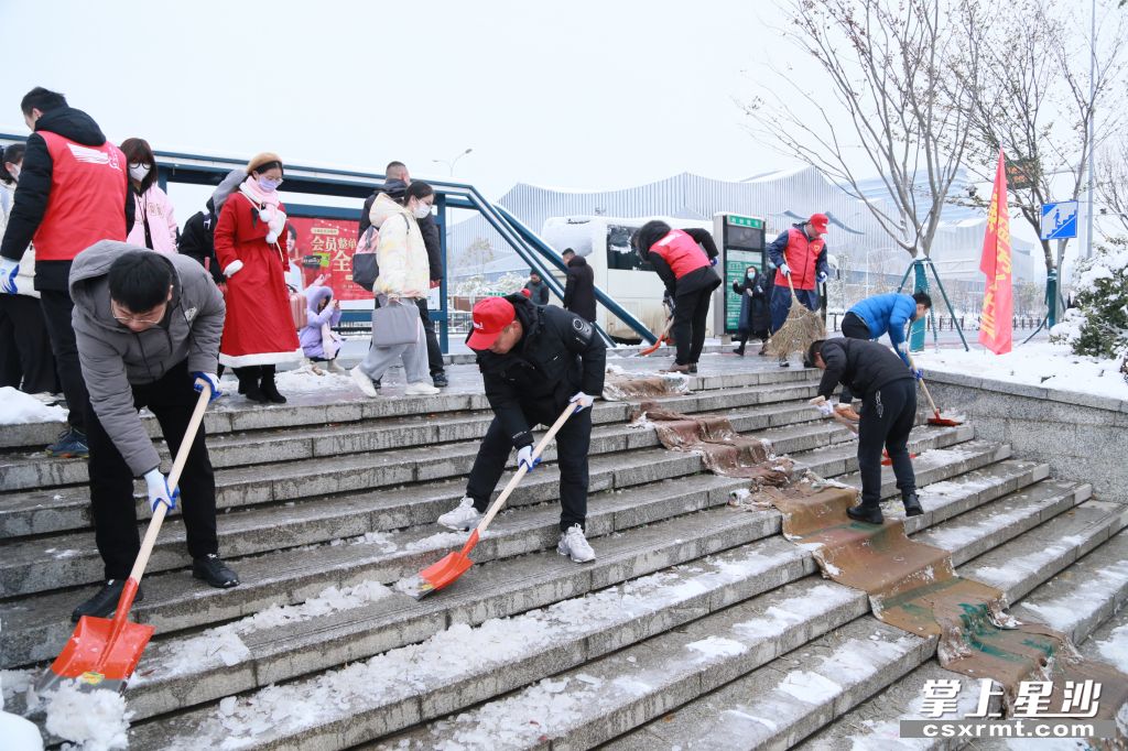 长沙县黄兴镇机关党员干部清扫光达地铁站台阶上的积冰，为群众出行提供便利。